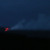 A blurry nighttime photo of glowing lava reaching the water in the distance